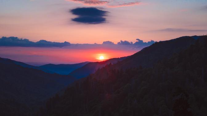 The sun melting into the ground behind the Smoky Mountains